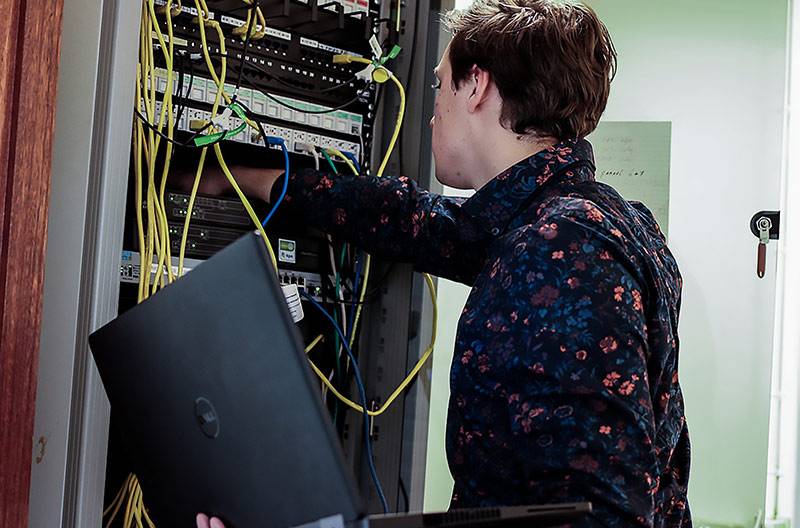A man reaching into a server rack demonstrating the skill of network administration